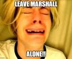 A person with light hair, crying with visible tears, is in the middle of the frame. The text "LEAVE MARSHALL" is above the person and "ALONE!!" is below them. The background is a plain tan-like surface.