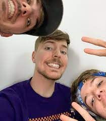 A selfie of three guys smiling at the camera. One is positioned at the top of the frame, angled upside down. Another one is in the middle, looking directly at the viewer. The third one is at the bottom right of the image, tilted toward the viewer.