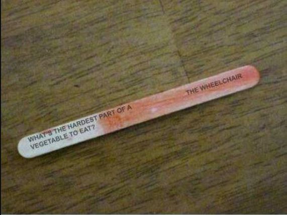 The image shows a popsicle stick with a riddle printed on it: "What's the hardest part of a vegetable to eat?" The answer is printed on the other side of the stick: "The wheelchair."