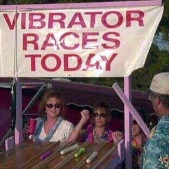 A banner that says "VIBRATOR RACES TODAY" hangs over a booth where multiple vibrators are laid out on a table.