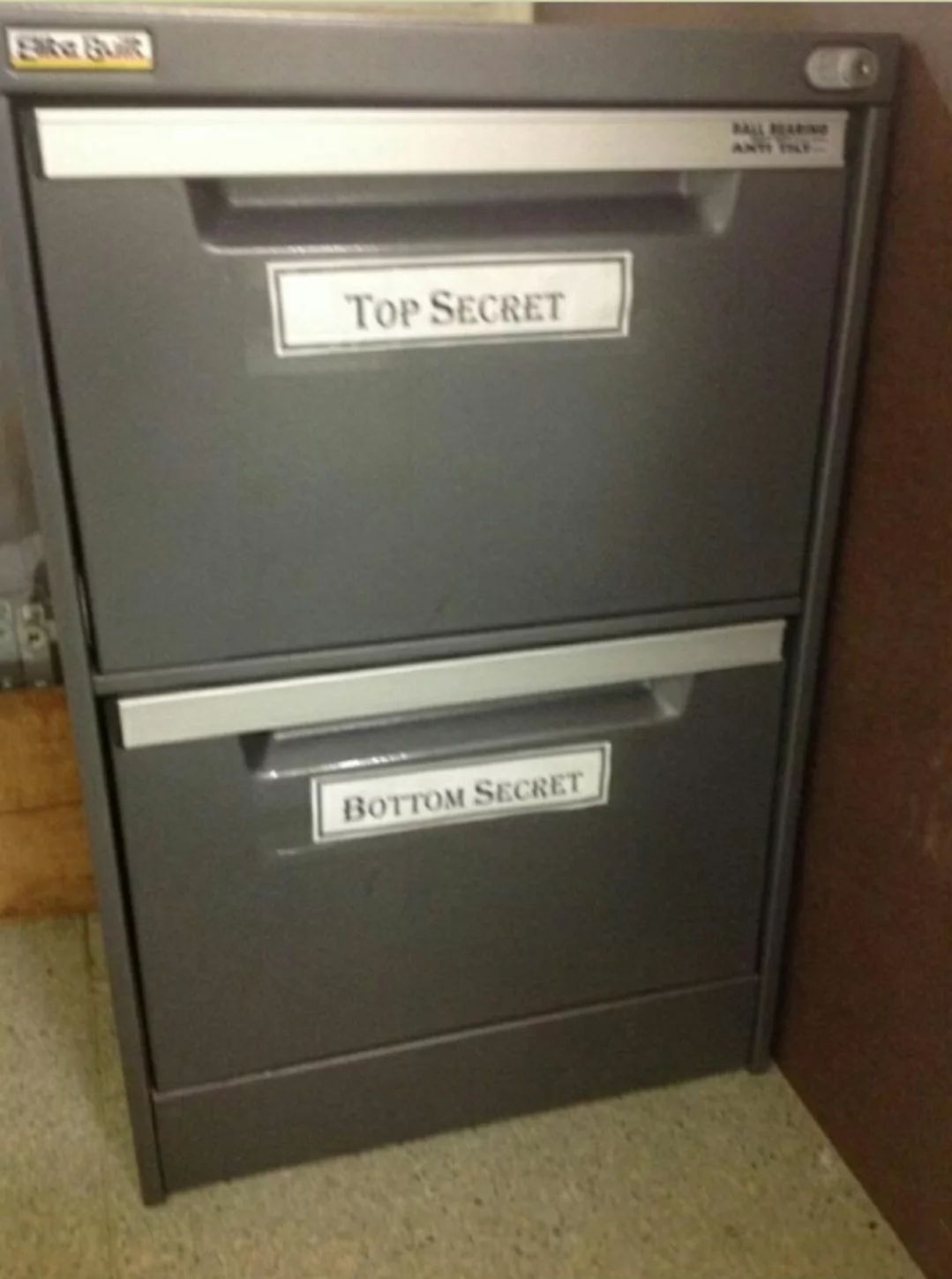 A file cabinet with two drawers. The top drawer has a label that reads "Top Secret" and the bottom drawer has a label that reads "Bottom Secret".