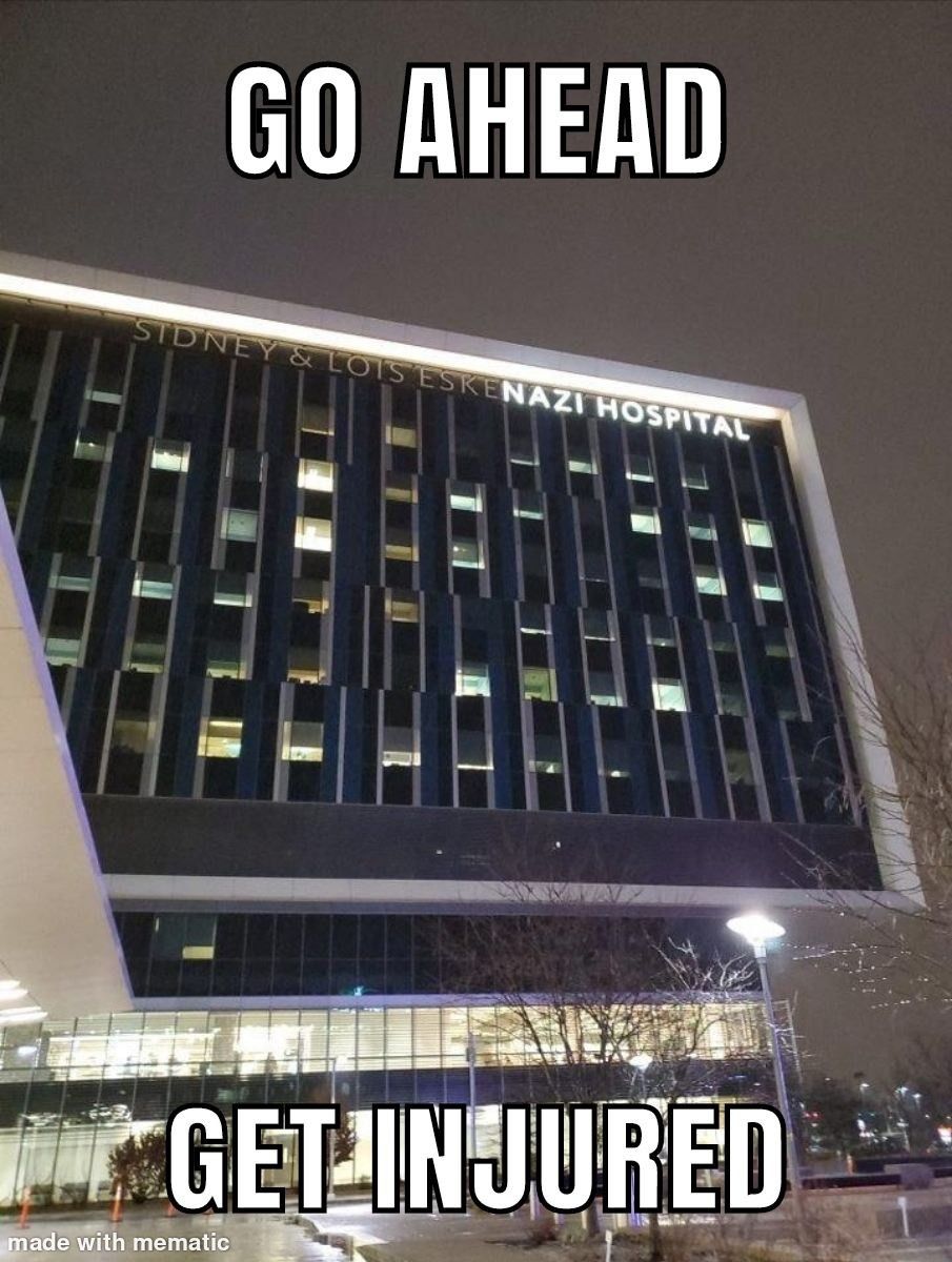 A photograph of the Sidney & Lois Eskenazi Hospital at night, with the text "GO AHEAD" at the top and "GET INJURED" at the bottom.