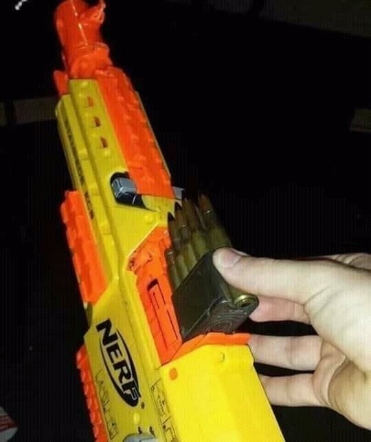 A hand is loading a magazine of real bullets into a yellow and orange Nerf gun.