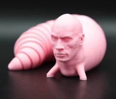 A pink, worm-like creature with a human face. The face is that of Dwayne Johnson. It is on a black background.