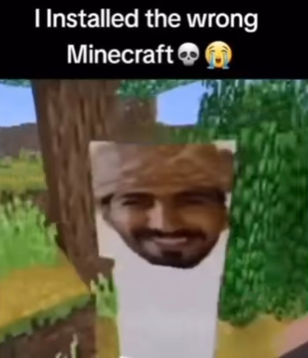 A screenshot from the video game Minecraft shows the game with a 2D-looking image of a smiling man with a headdress on his head. The image is placed on one of the game's objects (a tree or a block). The text on the image reads: "I installed the wrong Minecraft 💀😭".