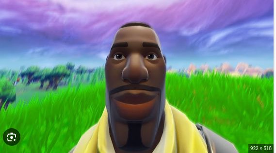 A close-up of a character's face from the video game Fortnite against a blurred background of a landscape. The character is looking straight at the viewer.