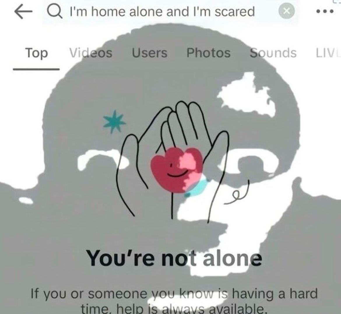 A person's face is silhouetted in gray, with hands holding a heart in the center. The text says, "You're not alone. If you or someone you know is having a hard time, help is always available."