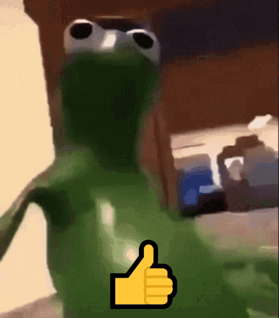 A green puppet with big eyes and a black shadow gives a thumbs up. The puppet is Kermit.