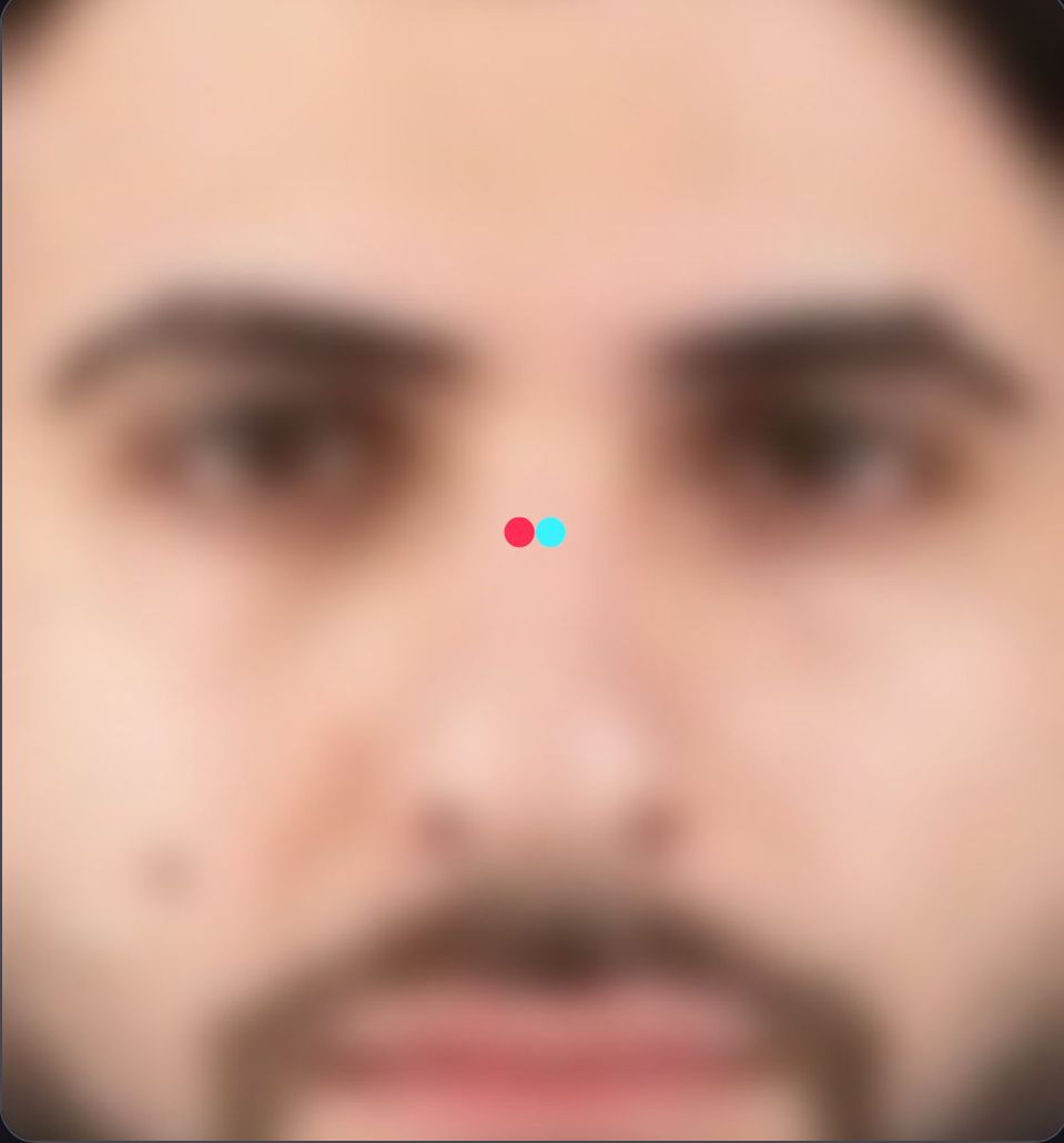 A blurry face with two dots of different colors on the nose, which resembles the TikTok logo.