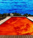 The image shows a pool filled with reddish-orange liquid, possibly lava, with a blue ocean in the background. The pool is surrounded by a light brown wooden border.